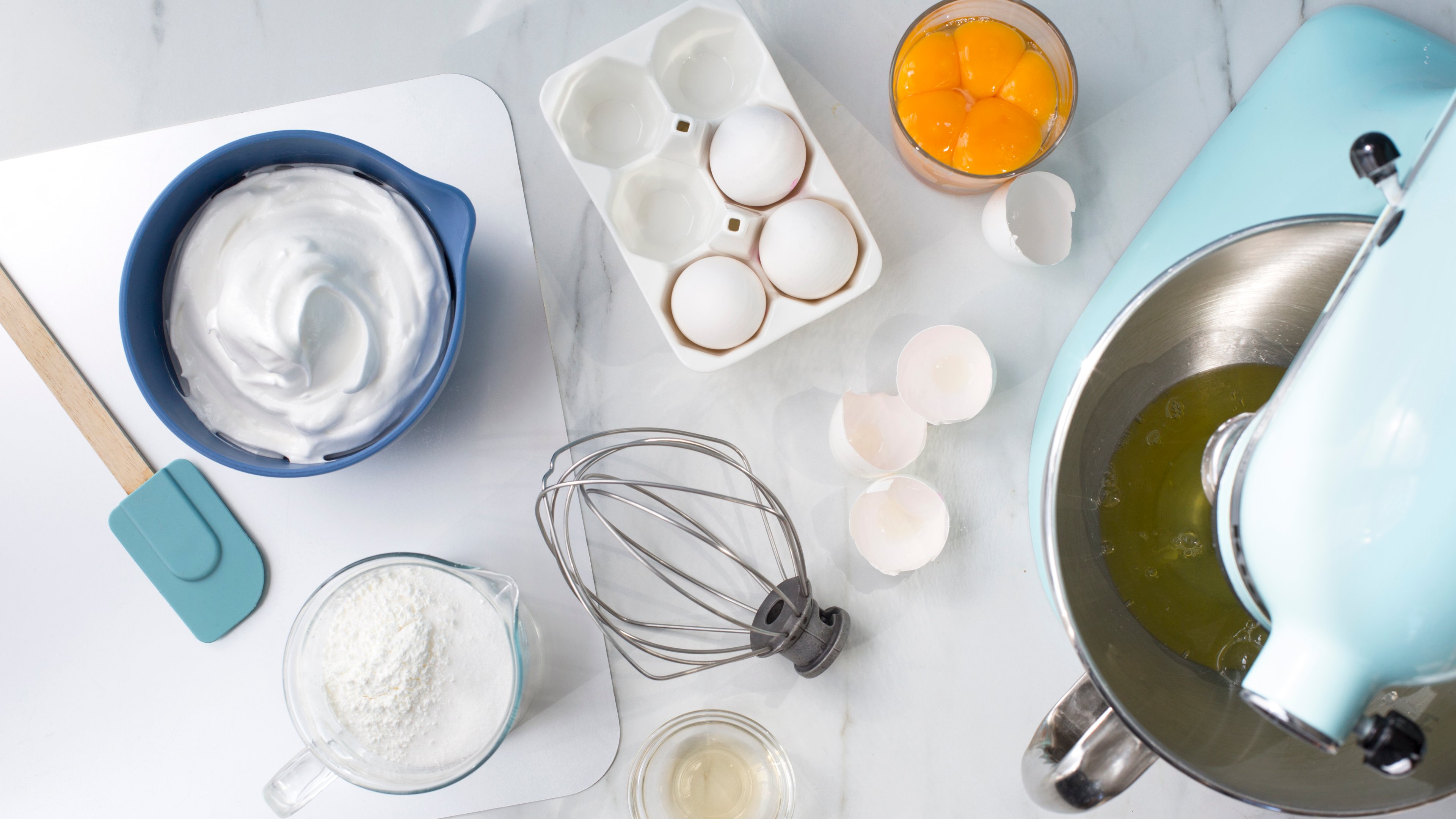 bildet viser et bord med, egg, eggehvite og kjøkkenmaskin. Alt du trenger for å lage marengs